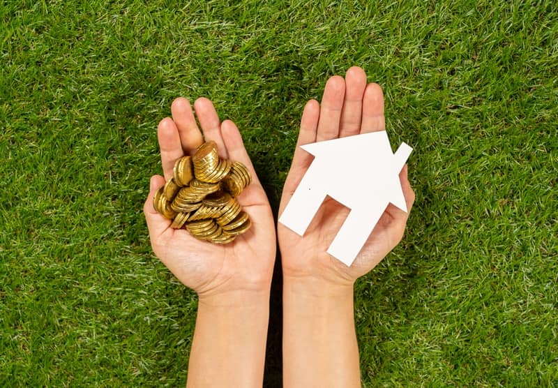 A house model beside a stack of coins, representing home equity